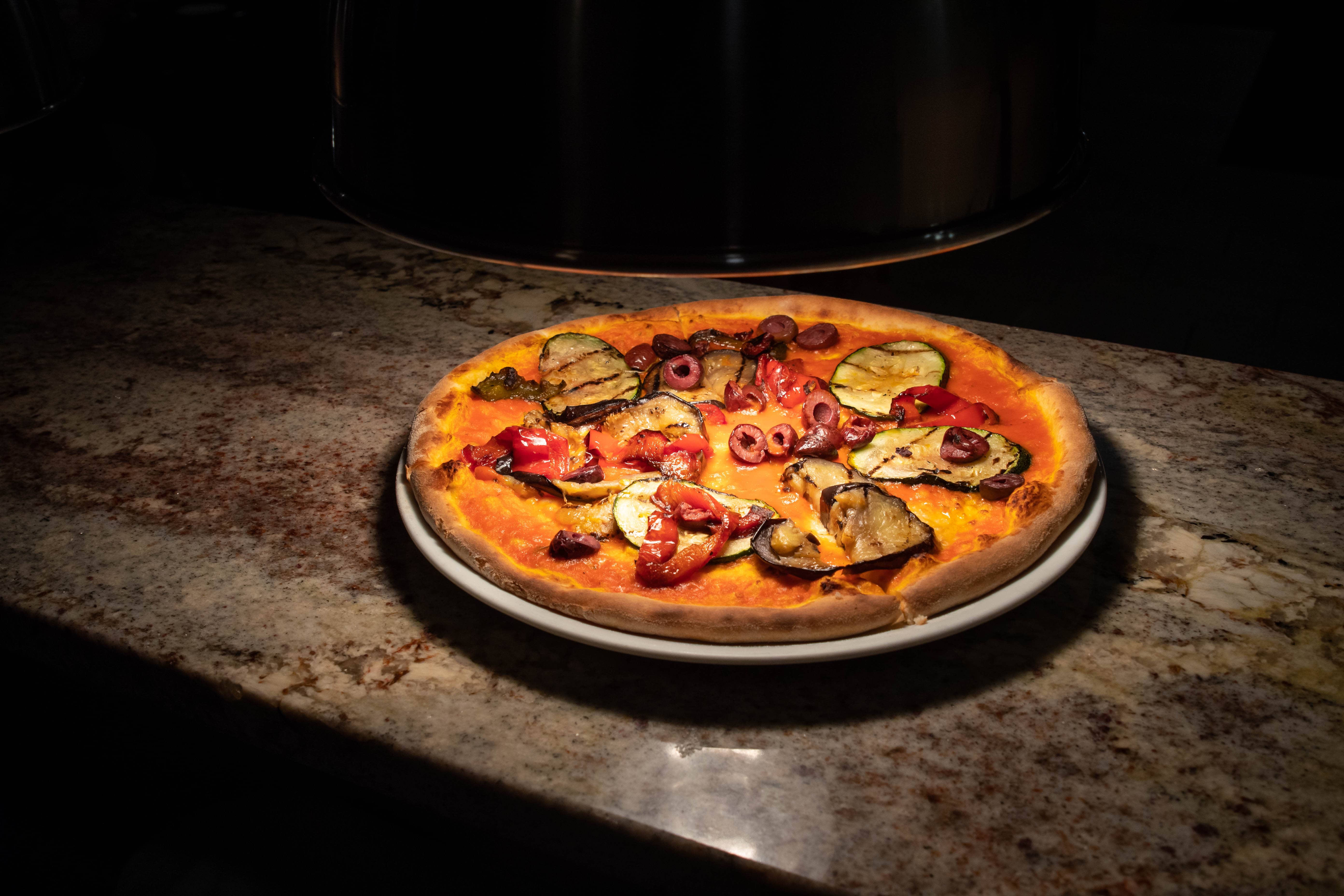 Brick Fired Oven Pizza topped with cheese olives pepper and zucchini eggplant