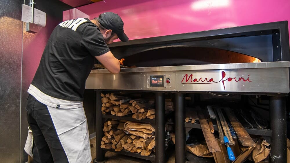 Pink Wood and Gas fired Marra Forni brick oven being operated by Bagel Chef