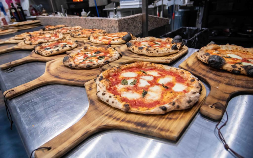 Line of Pizzas on wooden marra forni peels