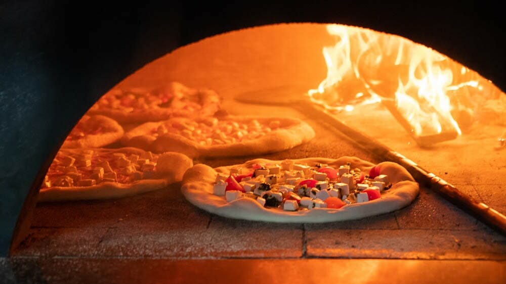 Five Neapolitan Pizzas baking in a wood fired marra forni brick oven